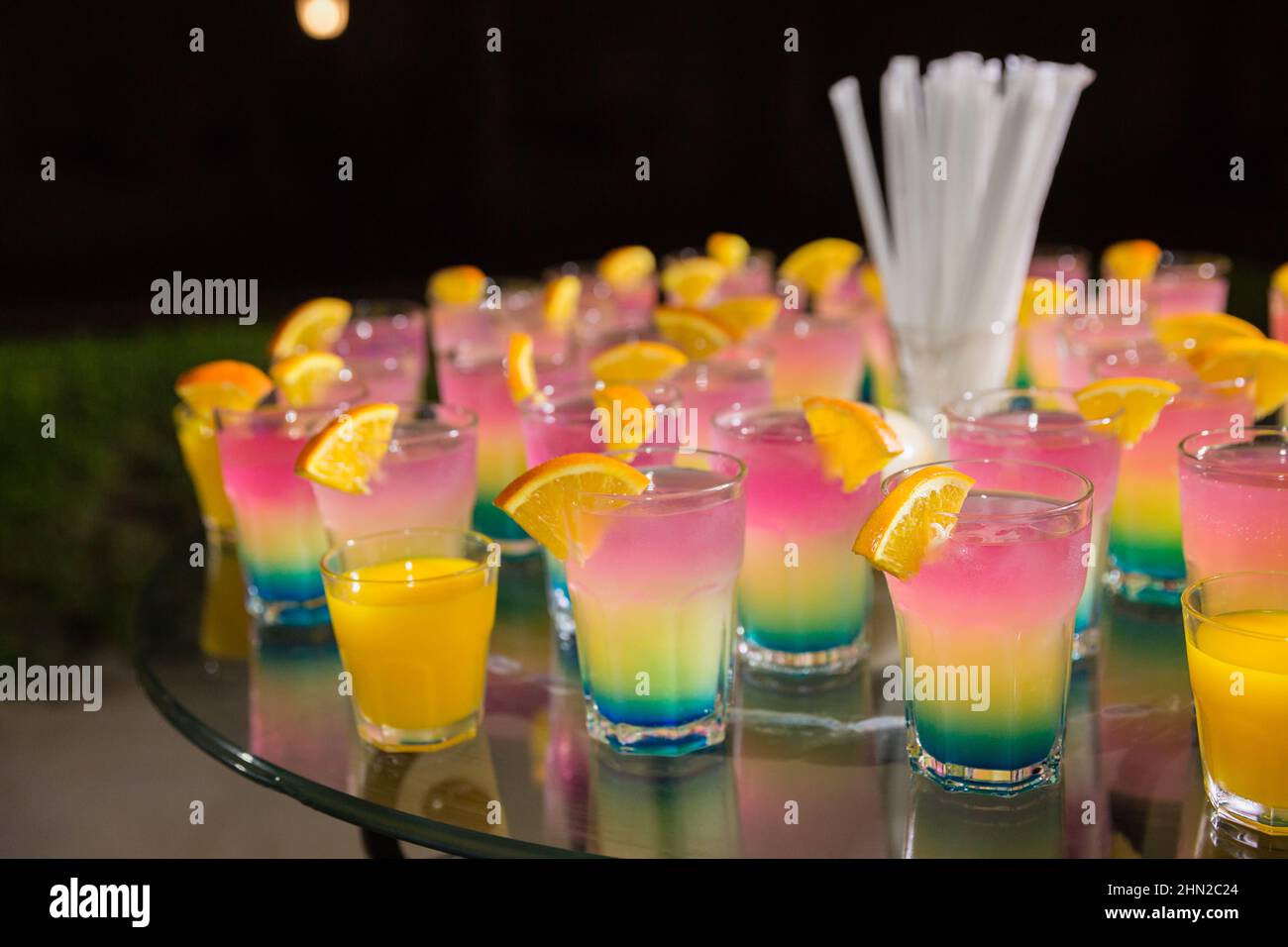Verschiedene farbige Alkoholcocktails mit Orangenscheiben auf einer Open-Air-Nachtparty im ägyptischen Hotel. Dekorierter Catering-Glastisch auf Open-Air-Veranstaltung Stockfoto