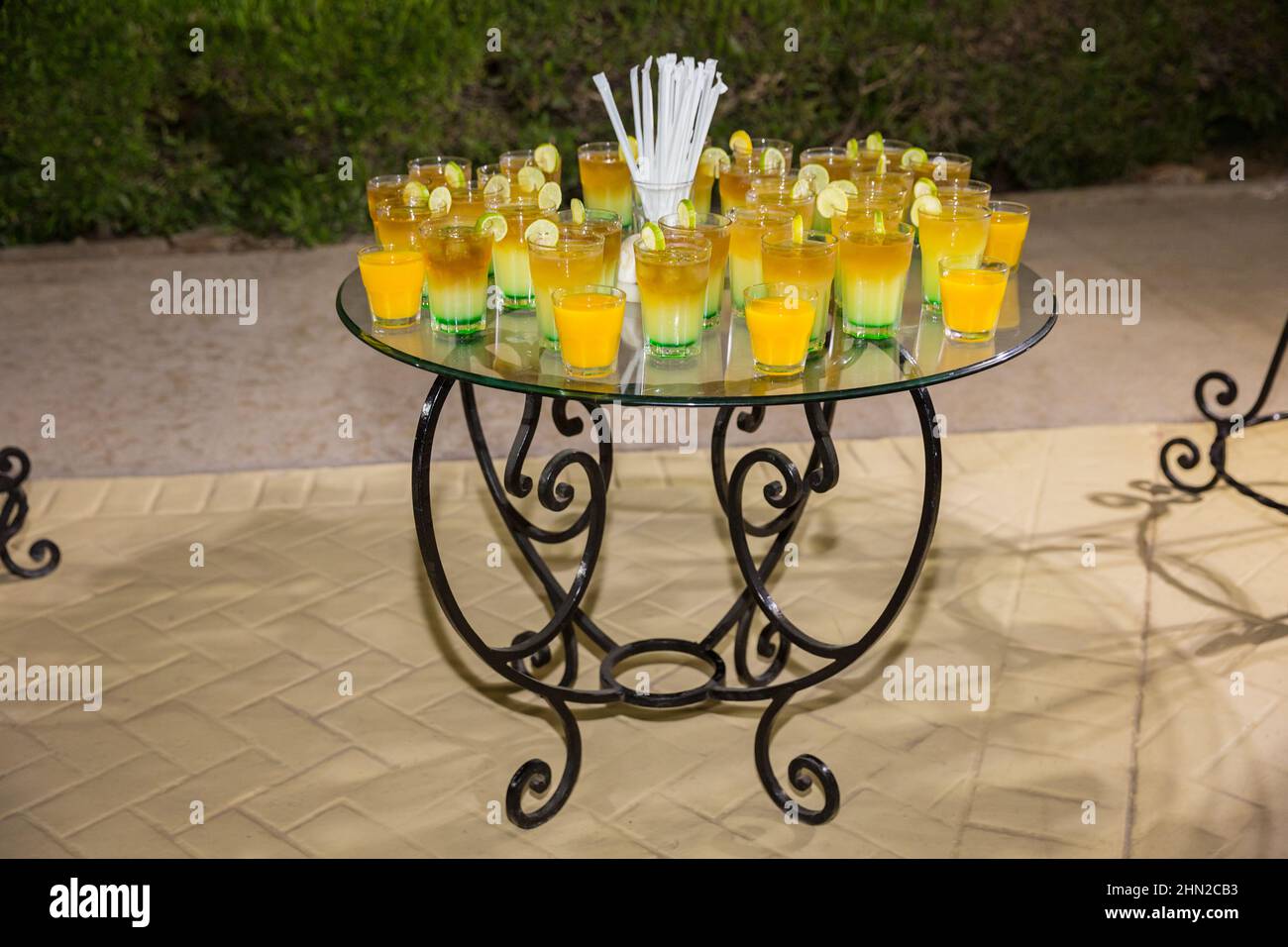 Verschiedene farbige Alkoholcocktails mit Orangenscheiben auf einer Open-Air-Nachtparty im ägyptischen Hotel. Dekorierter Catering-Glastisch auf Open-Air-Veranstaltung Stockfoto