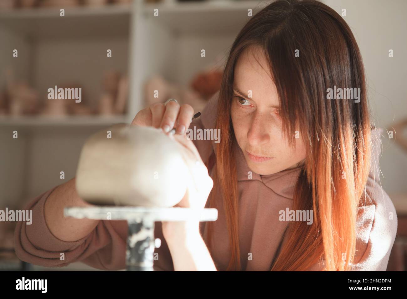 Nahaufnahme einer weiblichen Keramikerin, die beim Herstellen einer Tontanne fokussiert aussieht Stockfoto