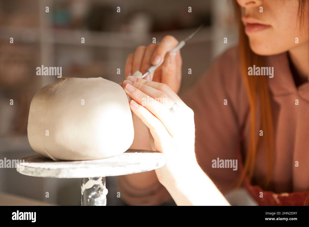 Beschnittene Nahaufnahme einer Teekannen aus Ton, an der eine Keramikerin in ihrem Kunststudio arbeitet Stockfoto