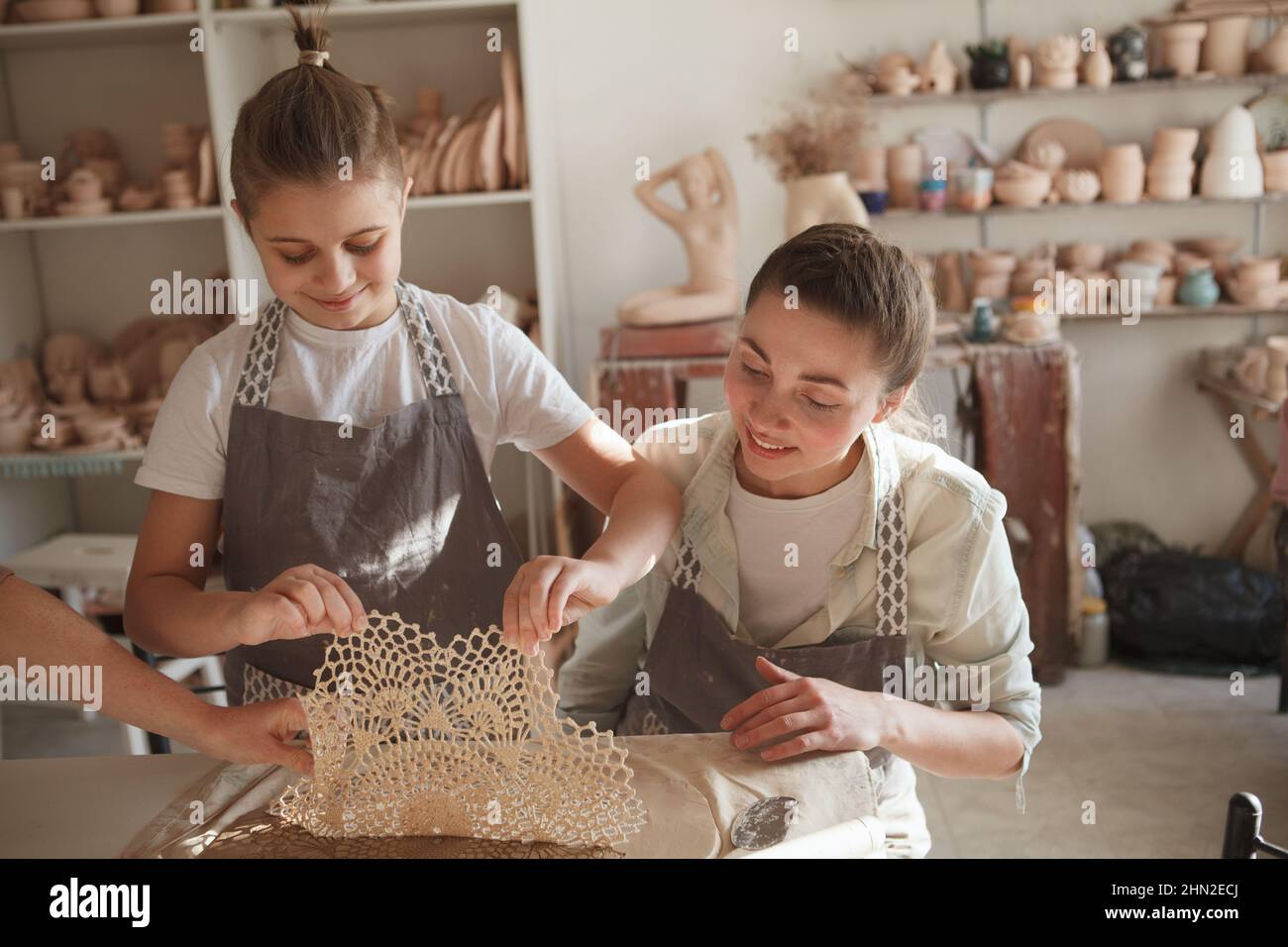 Fröhlicher junger Junge und seine Mutter bereiten Ton zu Geschirr im Töpferunterricht zu machen Stockfoto
