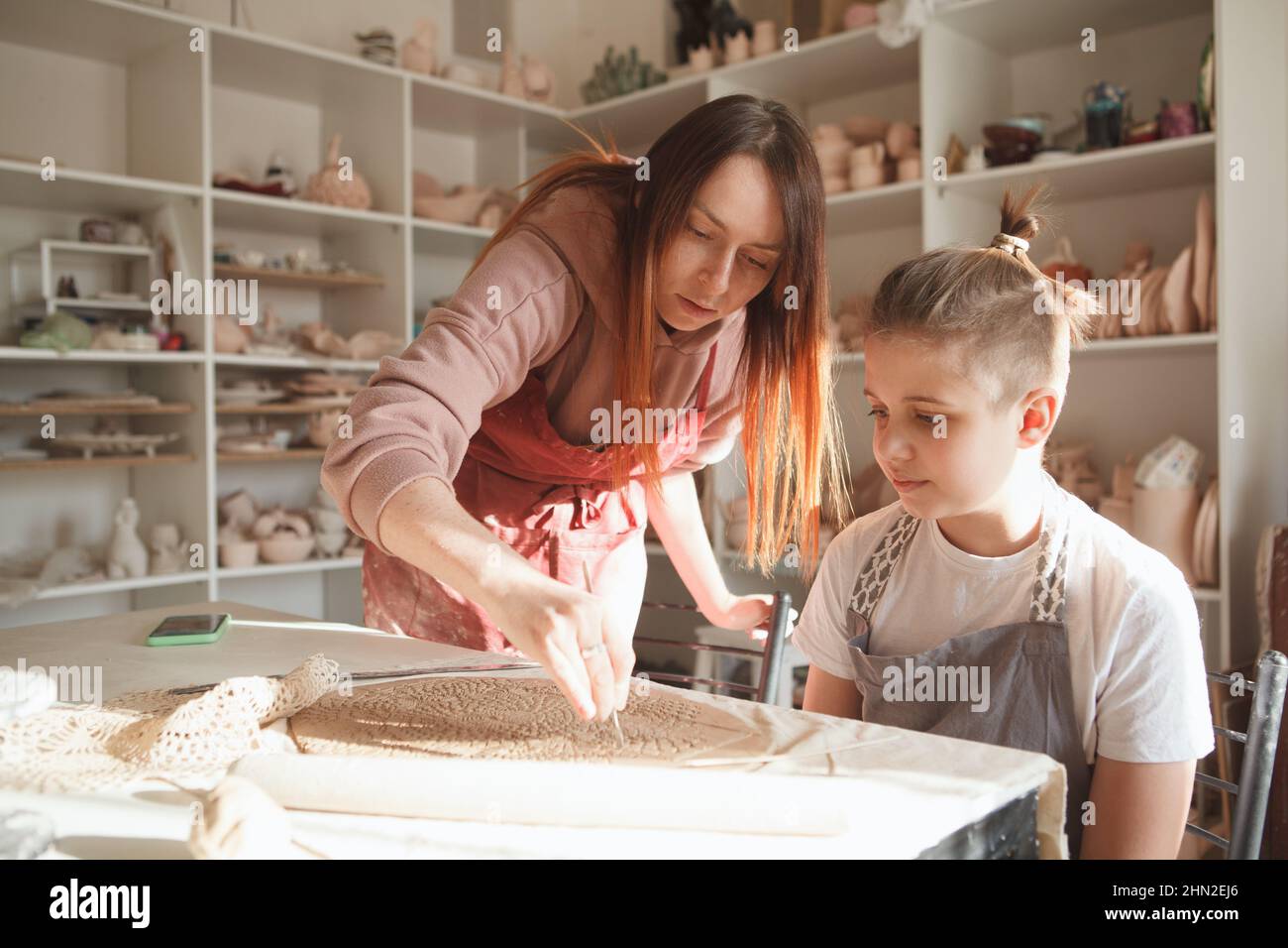 Professioneller Keramiker, der einem kleinen Jungen Töpferei beibringt, Raum kopieren Stockfoto