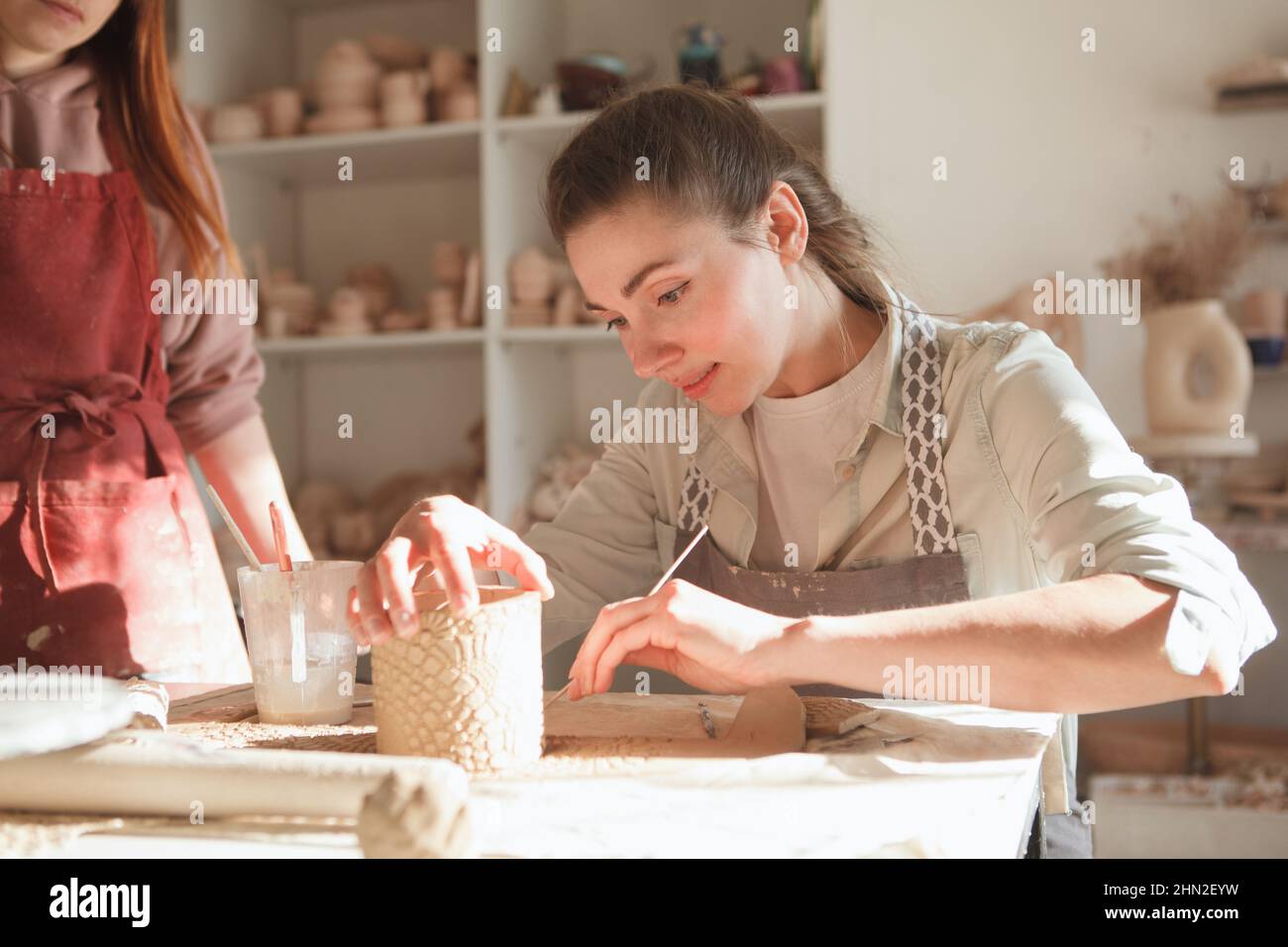 Schöne junge Frau macht Kaffeebecher bei Keramik-Klasse Stockfoto