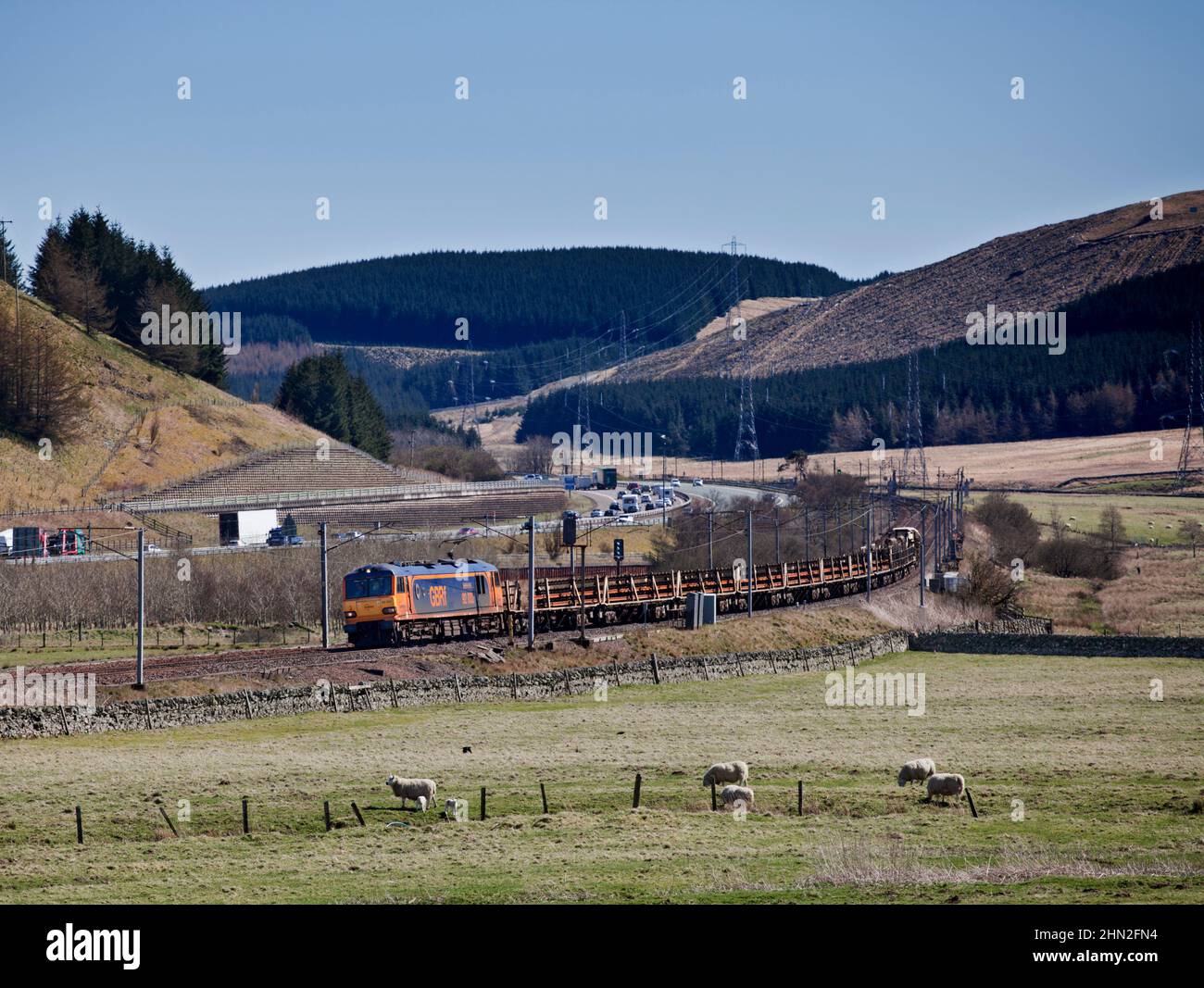 GB Railfreight Klasse 92 E-Lokomotive 92032 Passing Elvanfoot in the Clyde Valley mit einem Güterzug mit durchgehenden geschweißten Schienen Stockfoto