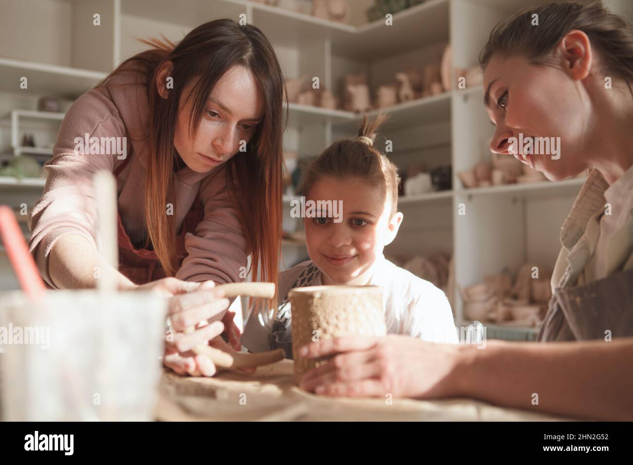 Kleiner Junge, der mit seiner Mutter und seinem professionellen Töpfer einen Keramikbecher machte Stockfoto