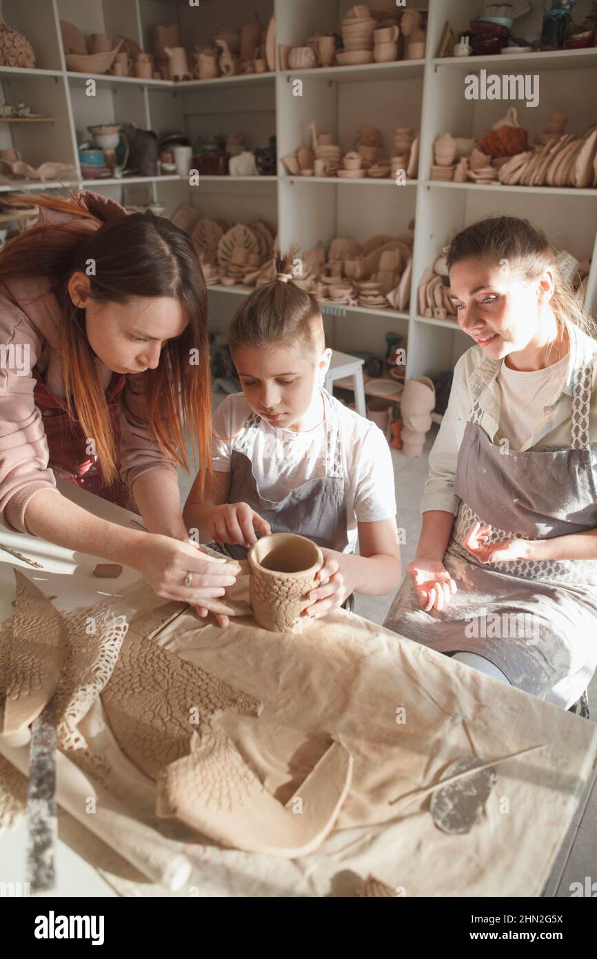 Draufsicht vertikale Aufnahme eines professionellen Keramikers, der Mutter und Sohn beim Herstellen von Geschirr aus Ton unterrichtet Stockfoto