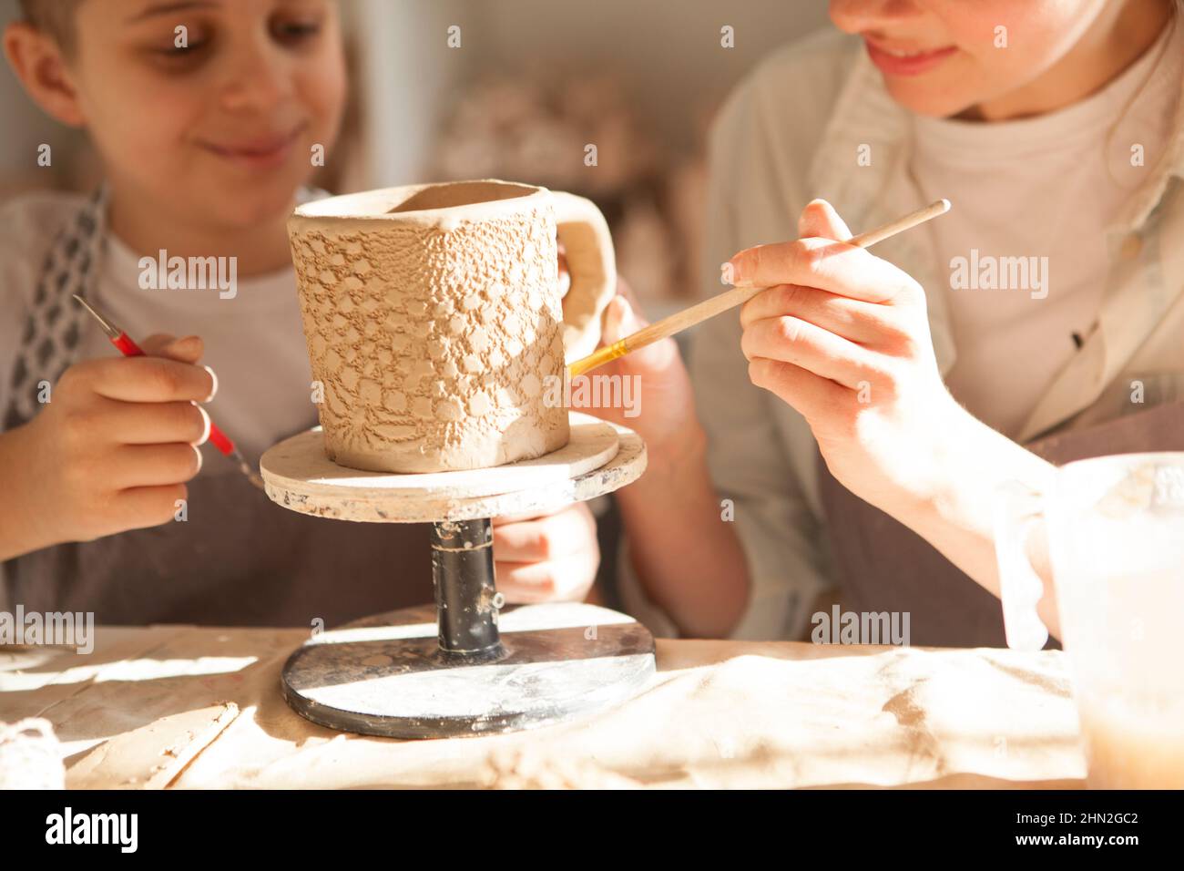 Nahaufnahme eines Keramikbechers, den Mutter und Sohn in der Kunstwerkstatt zusammen machen Stockfoto