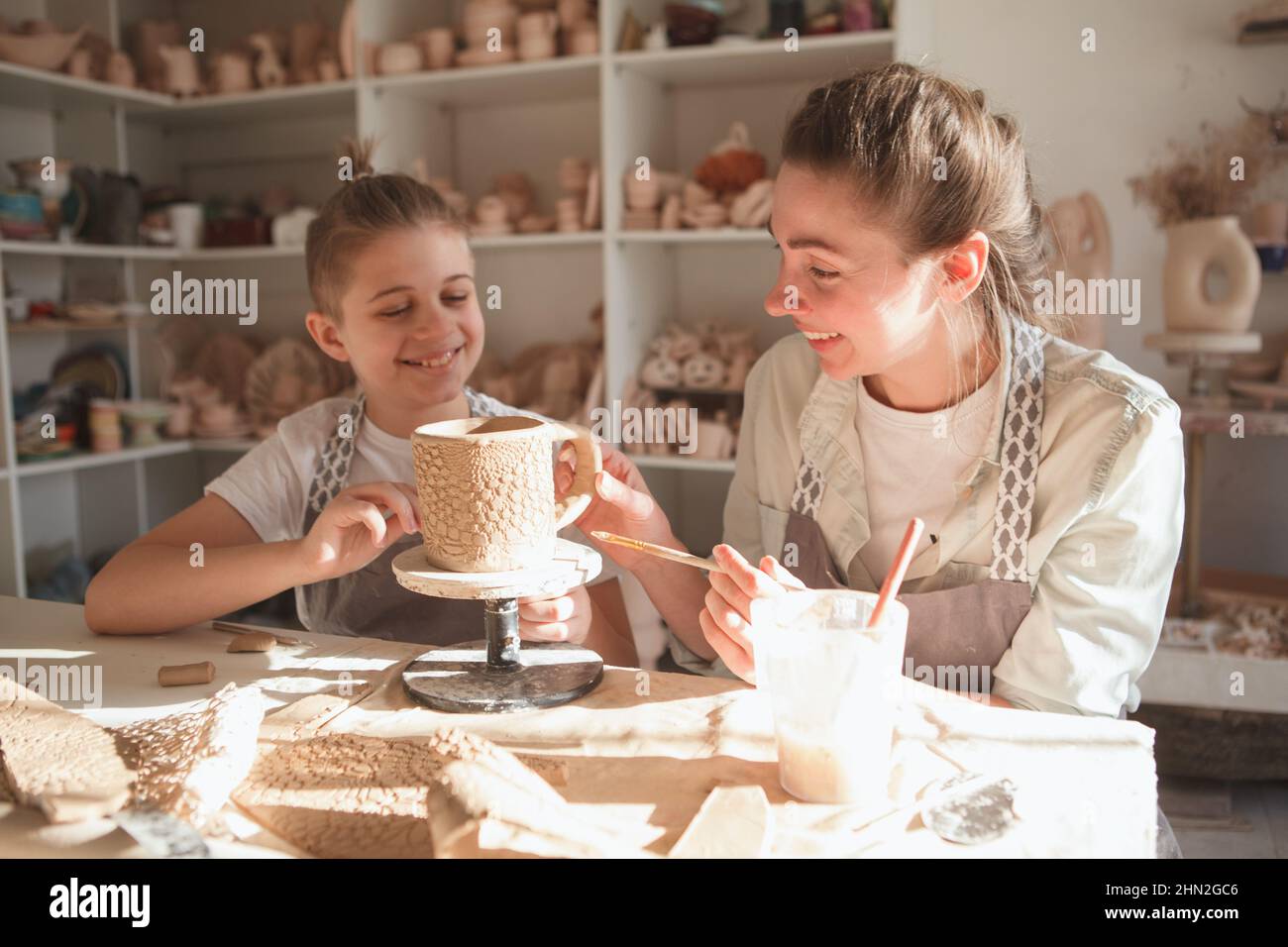 Kleiner Junge, der mit seiner Mutter lacht, während er gemeinsam im Töpferstudio Geschirr macht Stockfoto