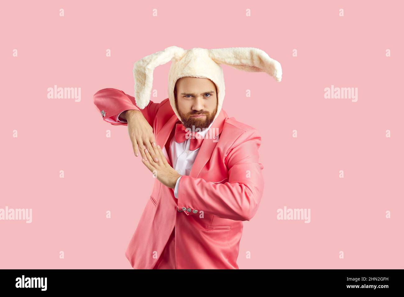 Fröhlicher Mann in lustigen flauschigen Hut mit Kaninchenohren gekleidet mit Spaß isoliert auf rosa Hintergrund. Stockfoto