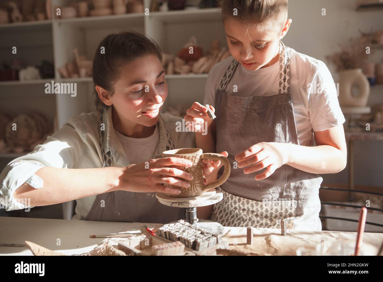 Der junge Junge und seine Mutter dekorieren handgemachtes Geschirr in der Kunstwerkstatt Stockfoto