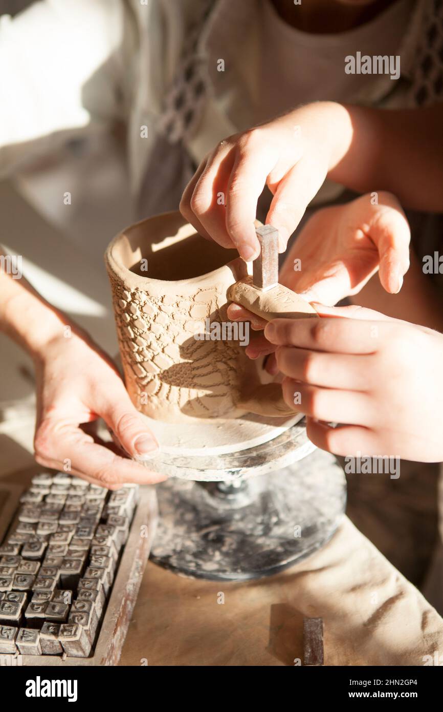 Vertikale Nahaufnahme des Kindes, das Eltern dabei hilft, Keramik mit Briefmarken zu dekorieren Stockfoto