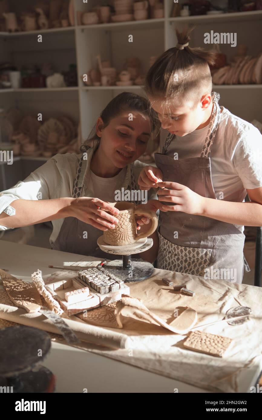 Vertikale Aufnahme einer charmanten Frau, die mit ihrem jungen Sohn in der Kunstwerkstatt gerne Keramik dekorieren würde Stockfoto