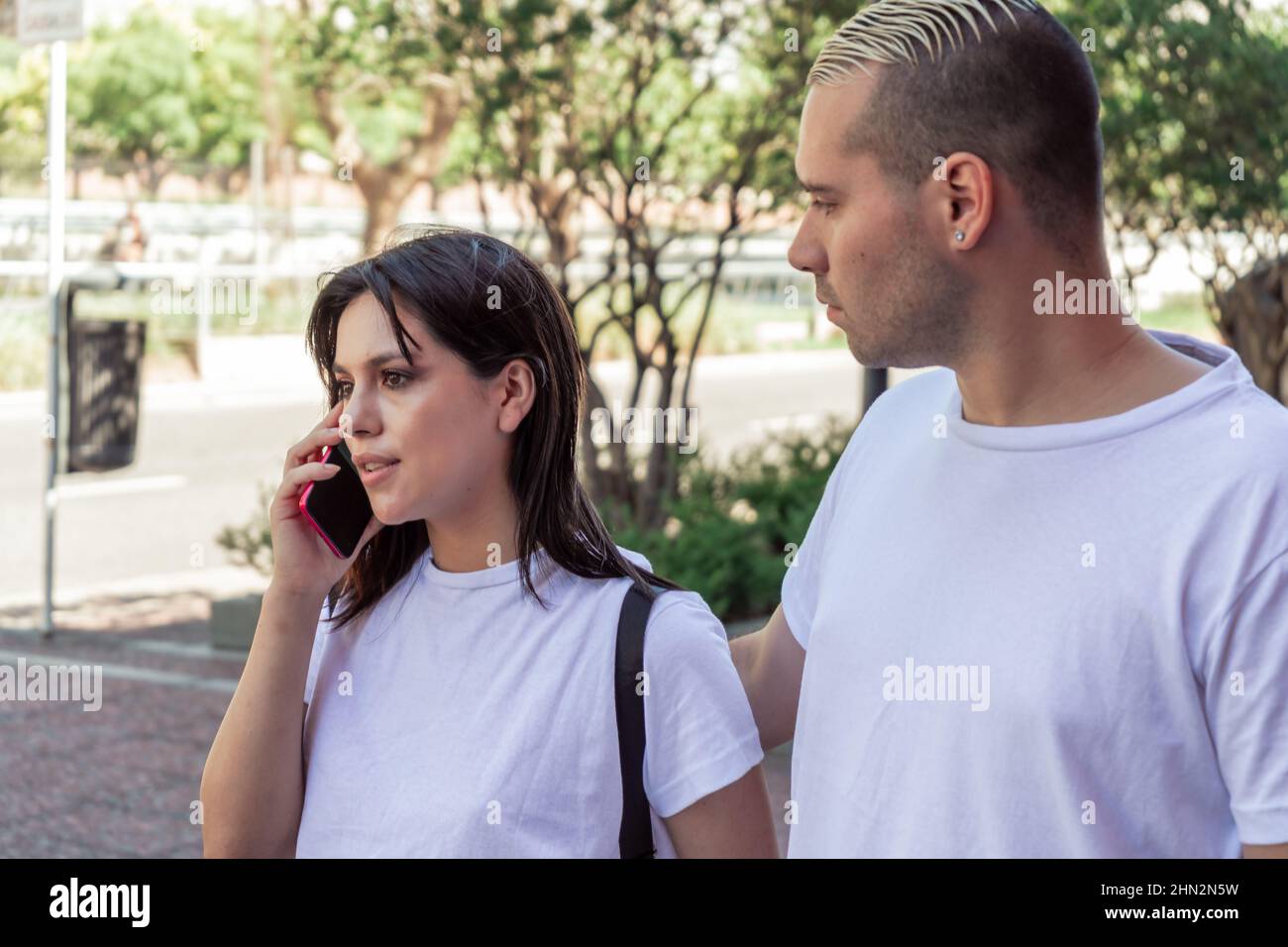 Nahaufnahme eines jungen lateinischen Paares, das läuft, während die Freundin am Handy spricht. Konzept-Technologie Stockfoto