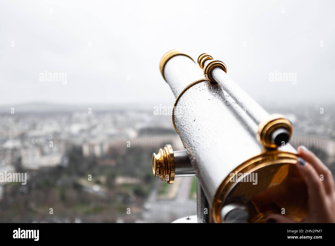 Altes Metallmonokular mit Regentropfen auf einer verschwommenen Stadtlandschaft Stockfoto