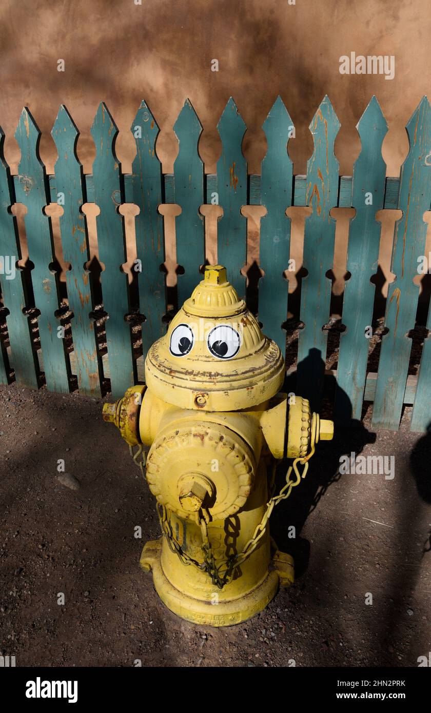Ein gelber Hydrant mit humorvollen Augen, der in Santa Fe, New Mexico, angebracht wurde. Stockfoto