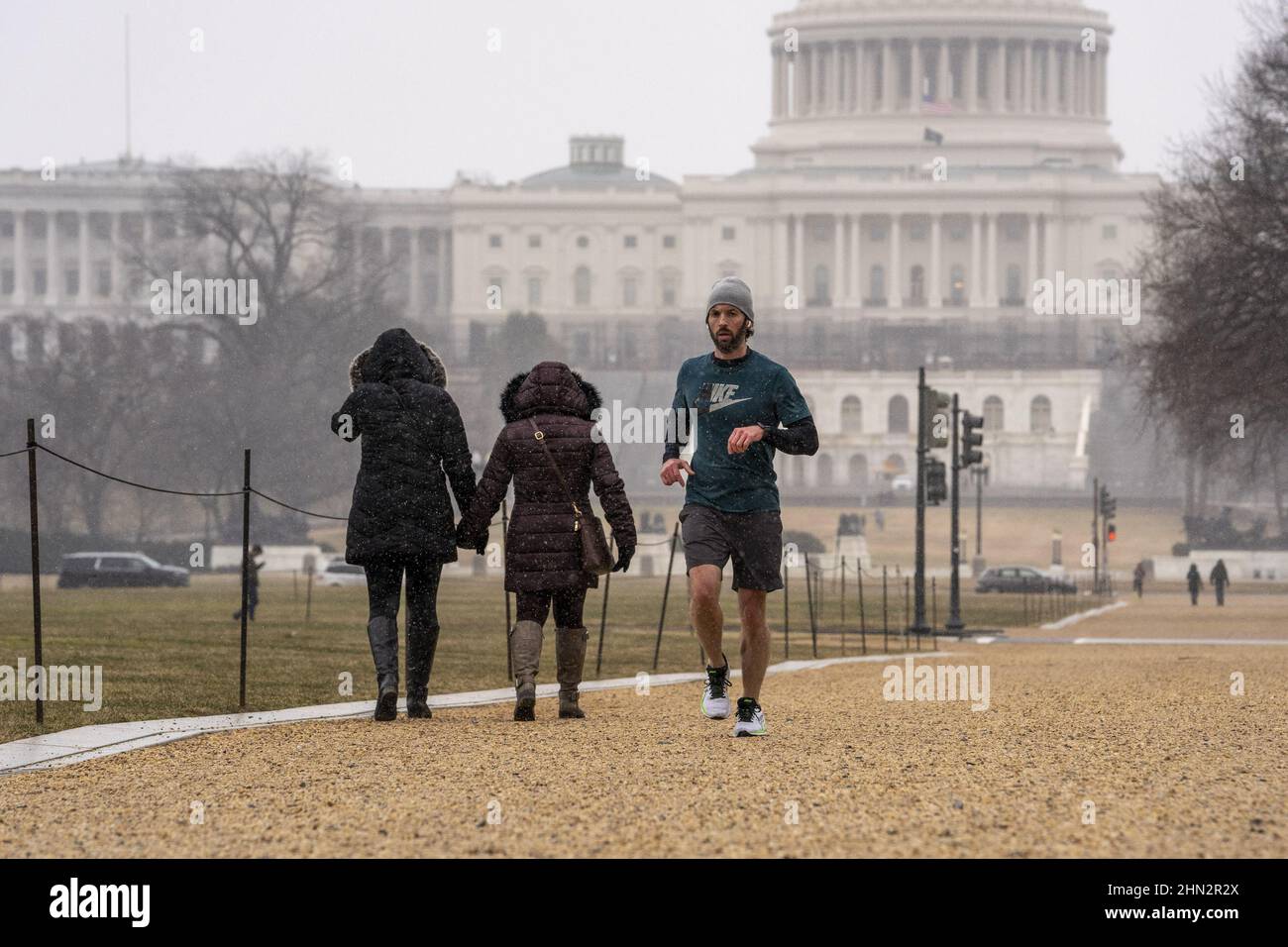 Washington, Usa. 13th. Februar 2022. Ein Mann joggt in der National Mall in der Nähe des US-Kapitolgebäudes, als am Sonntag, den 13. Februar 2022 in Washington, DC, Schneegestöber fallen. Foto von Ken Cedeno/UPI Credit: UPI/Alamy Live News Stockfoto