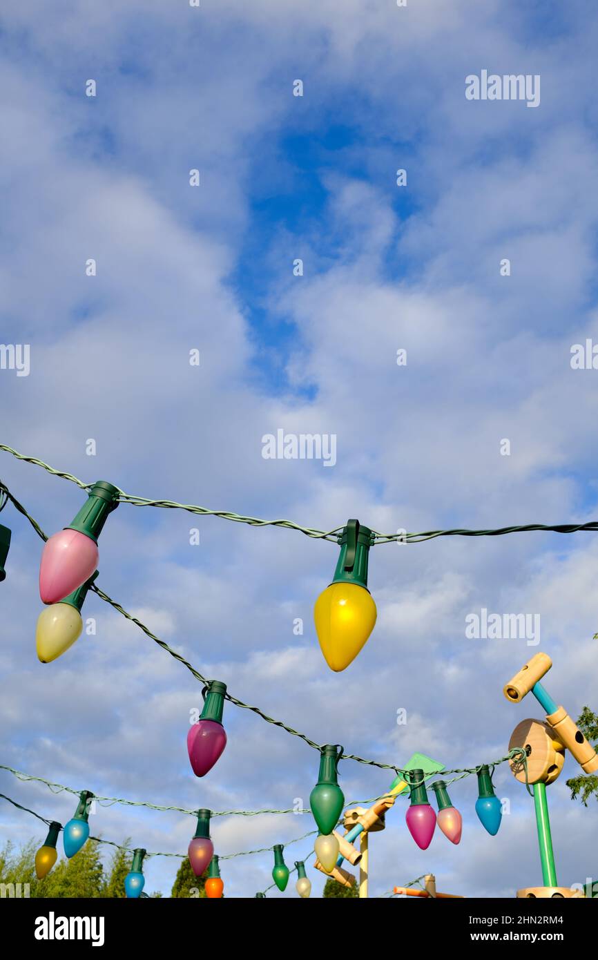 Bunte Glühbirnen als Dekorationsartikel auf einem blau bewölkten Himmel auf einer Party Stockfoto