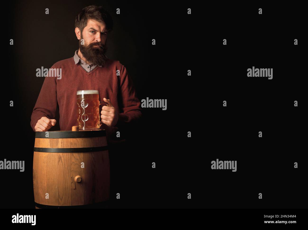 Fröhlicher Brauer. Emotionaler lustiger bärtiger betrunkener Hipster hält Craft-Flaschenbier. Fröhlicher Brauer, der Glas mit Bier hält. Glücklicher lächelnder Mann mit Bier. Stockfoto