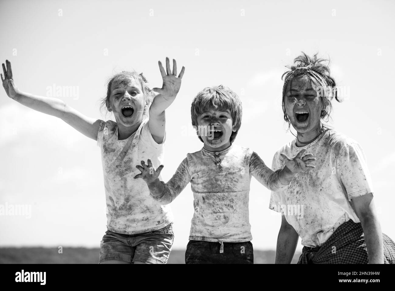 Lustige Kinder Gesicht in Farbe Splash, farbige Pulver auf Kinder Körper. Fröhliche Freunde zeigen Hände in hellen Farben gemalt. Bunte, schmutzige Leute. Stockfoto