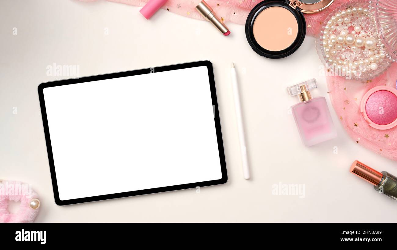 Weiblicher Arbeitsplatz, femininer Schreibtisch mit weißem Tablet-Bildschirm-Mockup, Eingabestift, Make-up-Produkte und rosa Accessoires auf weißem Tischhintergrund. ov Stockfoto