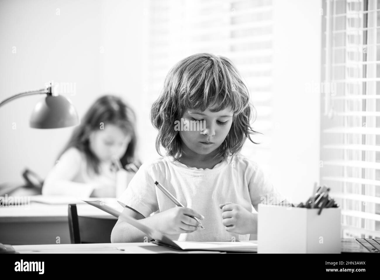 Nette Schüler schreiben am Schreibtisch im Klassenzimmer in der Grundschule. Student Junge macht Test in der Grundschule. Kinder schreiben während des Unterrichts Notizen Stockfoto