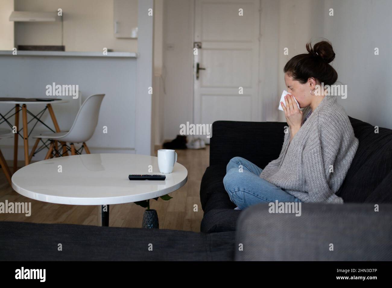 Eine kranke Frau hat eine laufende Nase, niest und bleibt zu Hause Stockfoto