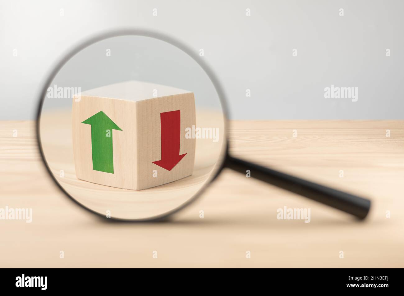 Analyse von Wirtschaftswachstum und Rückgang der Wirtschaft. Lupe und Holzwürfel mit grünem und rotem Pfeil. Suche nach Entscheidungen. Strategie für Anleger zur Abschreckungsstrategie Stockfoto