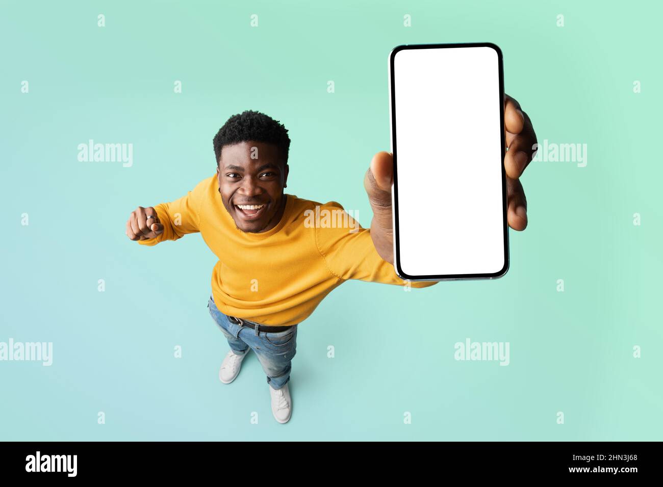 Aufgeregt schwarzen Kerl demonstriert Smartphone mit leeren weißen Bildschirm, zeigt freien Kopieplatz für Ihre Anzeige, mockup Stockfoto