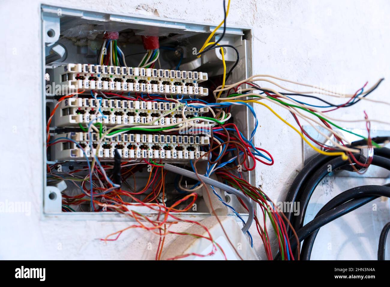 Offene Anschlussdose mit hervorstehenden Drähten, vorbereitet für die Montage und den Anschluss von Telefon- und Computerkabeln. Selektiver Fokus Stockfoto