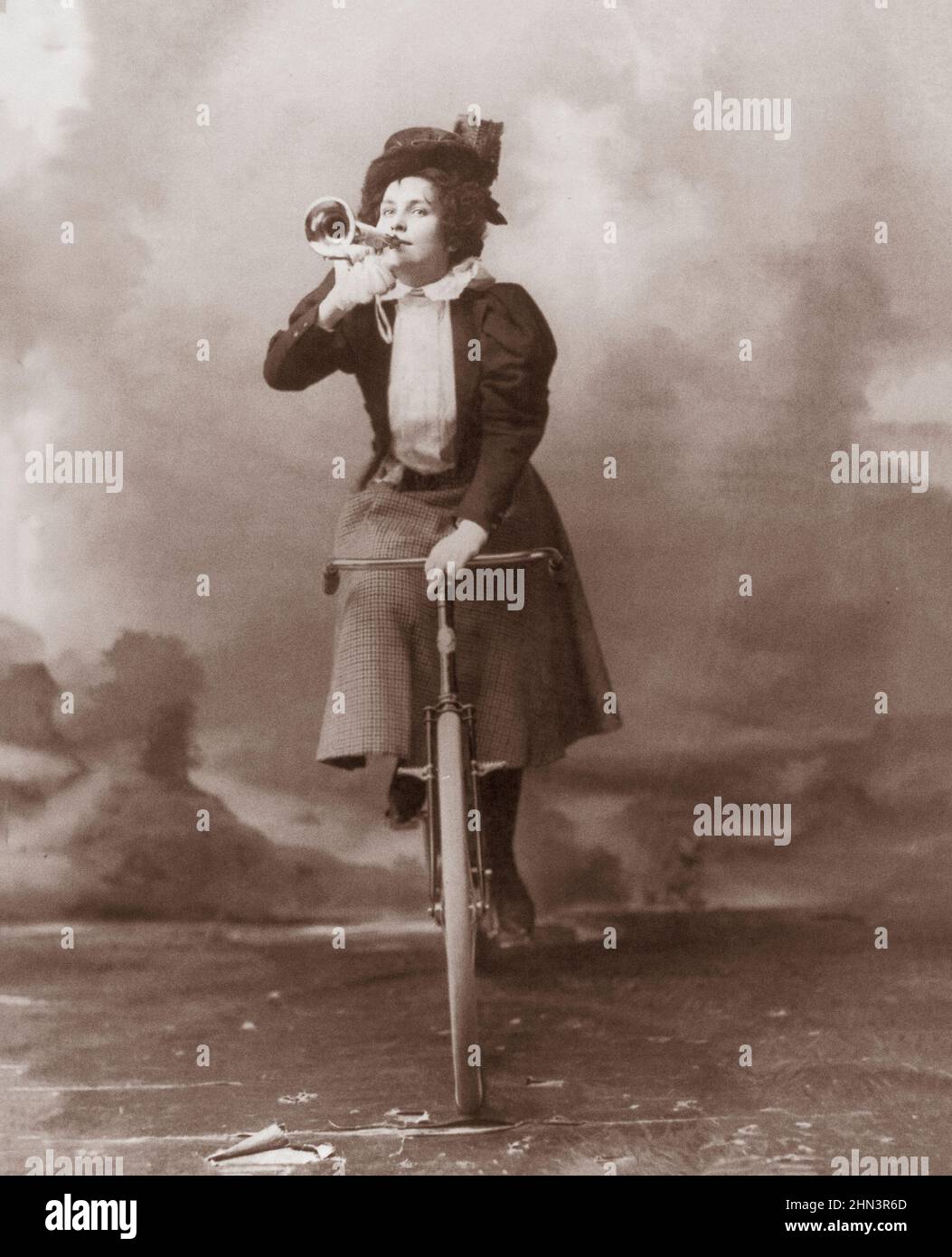 Vintage-Foto von Madge Lessing auf dem Fahrrad, das Musikhorn an den Lippen hält. 1898 Madge Lessing (1873 – 1966) war eine britische Bühnenschauspielerin und Sängerin, Pant Stockfoto