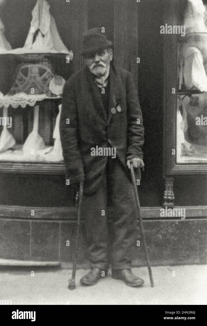 Vintage-Foto eines behinderten Veteranen, der mit zwei Stöcken und zwei Medaillen auf der Brust steht. Wien, Österreich (vor 1918 - Österreich-Ungarn). 19 Stockfoto