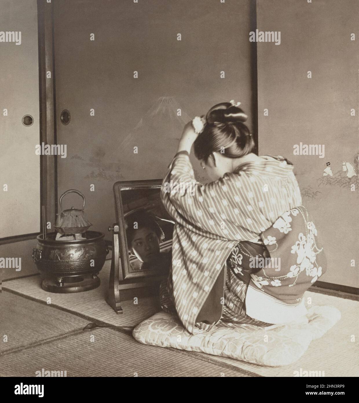 Vintage-Foto einer japanischen Frau im traditionellen Kimono, die im Spiegel aussieht. 1905 Stockfoto