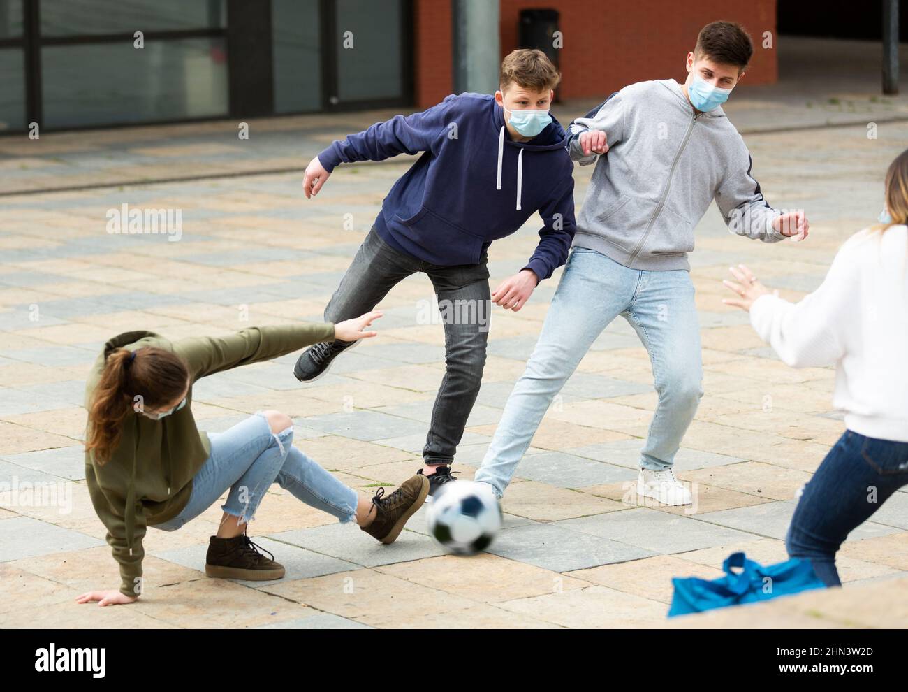 Jugendliche in schützenden Gesichtsmasken spielen Fußball Stockfoto