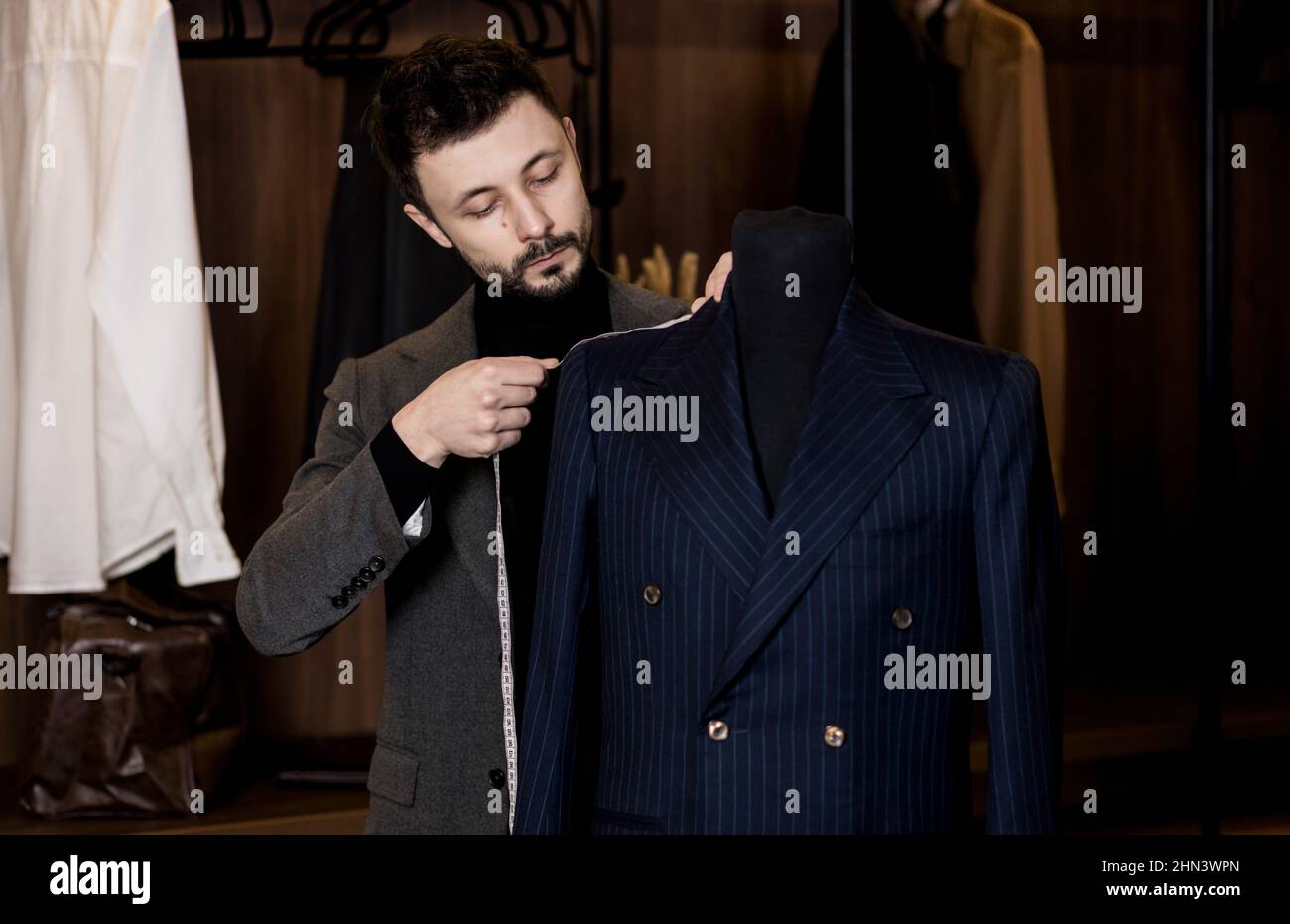 Junge Schneiderin in der Werkstatt. Modedesignerin nimmt Messungen von einer Schaufensterpuppe Stockfoto