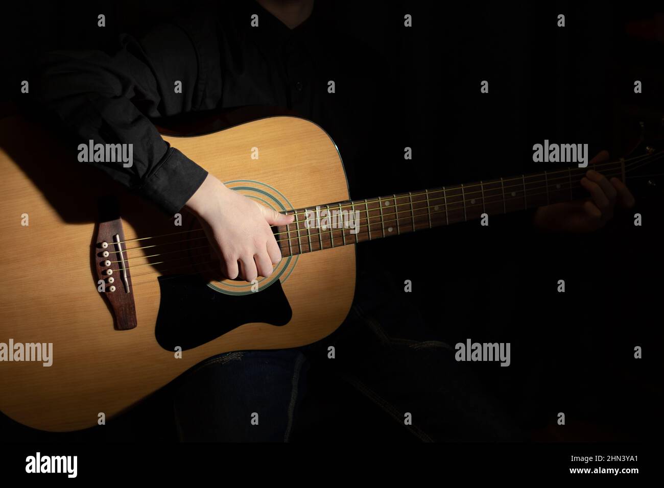 Hände eines Musikers, der eine akustische Gitarre mit Metallsaiten spielt. Hobby. Musikinstrumente. Selektiver Fokus. Nahaufnahme Stockfoto