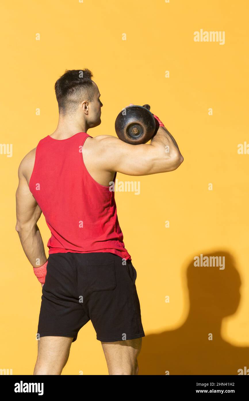 Starker, athletischer Mann mit Kettelglocke vor gelbem Hintergrund Stockfoto