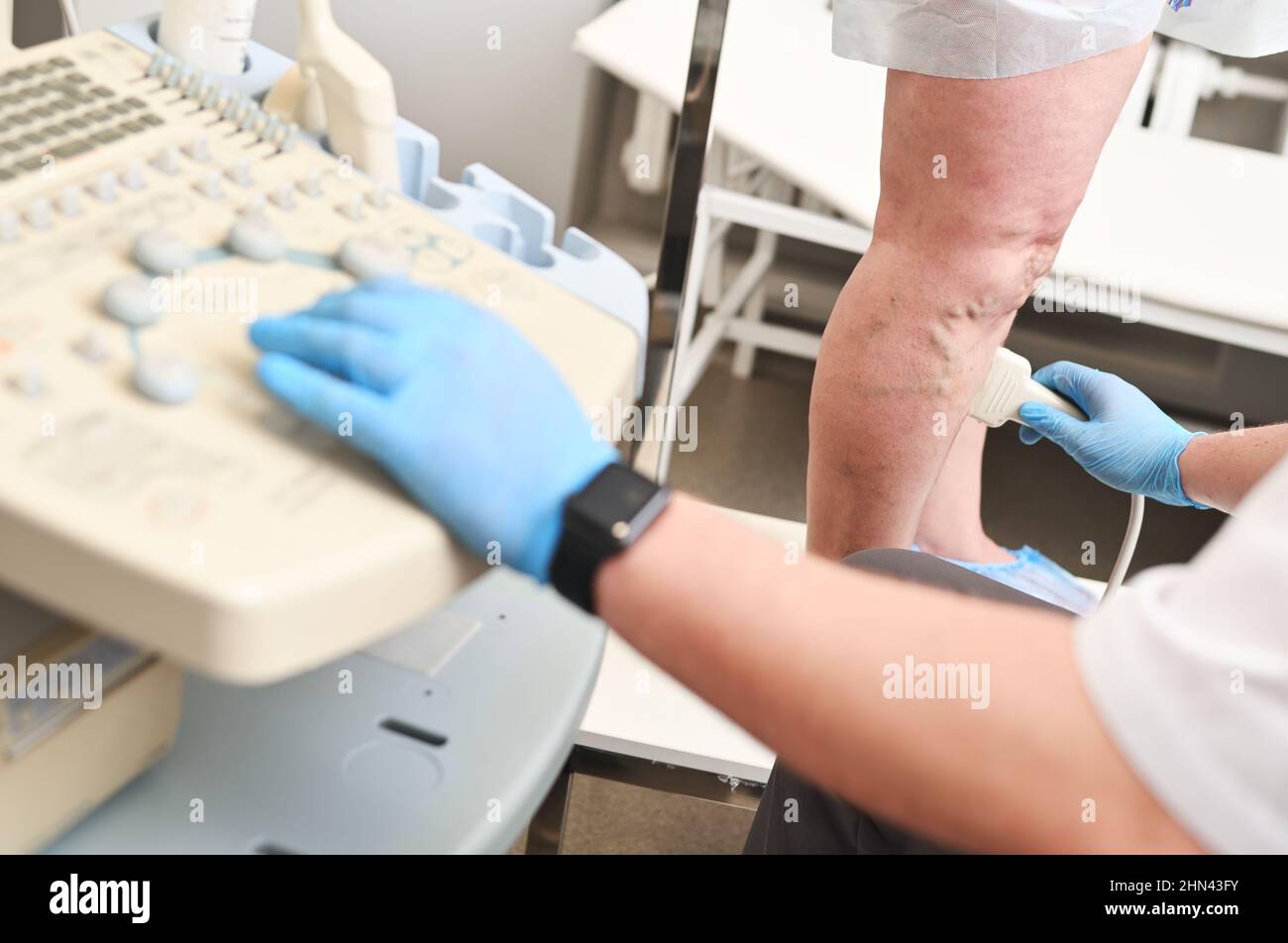 Ein Phlebologe führt eine Ultraschalluntersuchung der Venen eines Patienten mit Krampfadern durch. Stockfoto