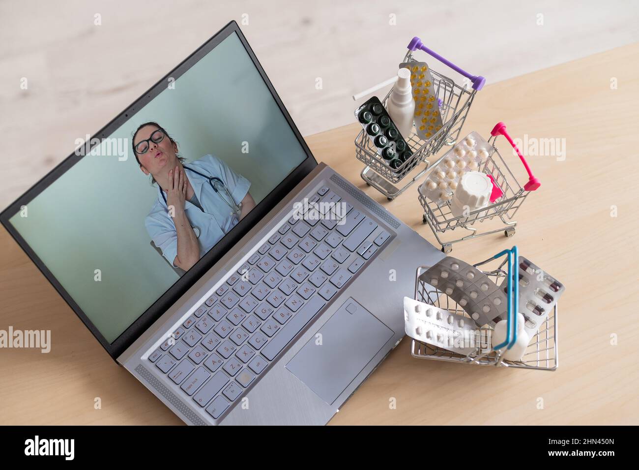 Online Medizin und Apotheke Konzept. Eine Ärztin führt eine Online-Konsultation durch und empfiehlt Medikamente. Mini-Trolley mit Tabletten am Stockfoto