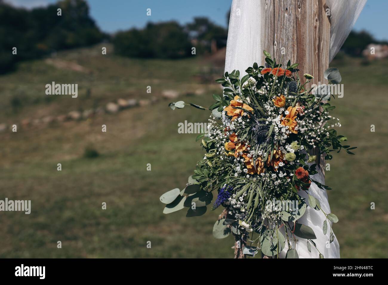 Florale dekorative Dekoration des weißen hölzernen Hochzeitsbogens mit frischen Blumen. Eine Farm halten, Boho Hochzeitszeremonie im Freien. Sommer Stockfoto