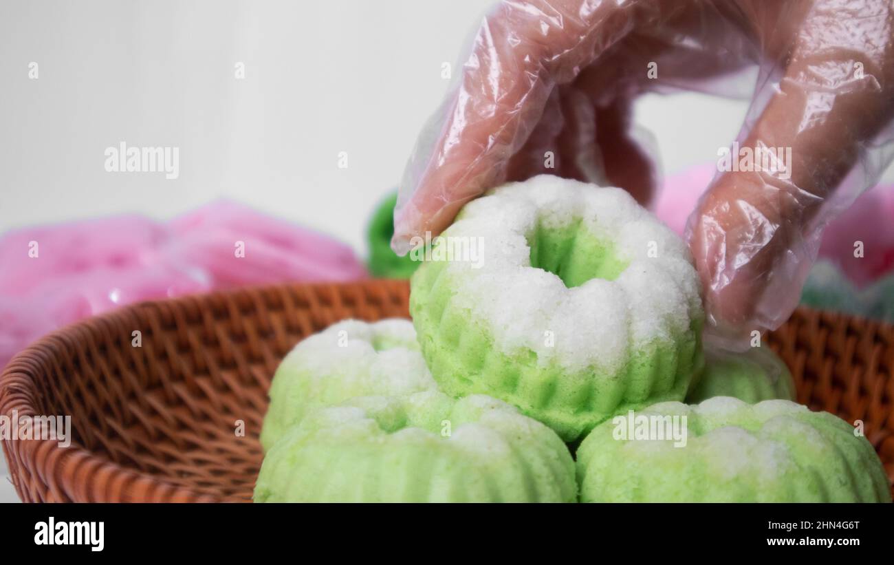 Eine Hand holt einen indonesischen gedünsteten Pandan-Kuchen mit Kokosnuss Stockfoto