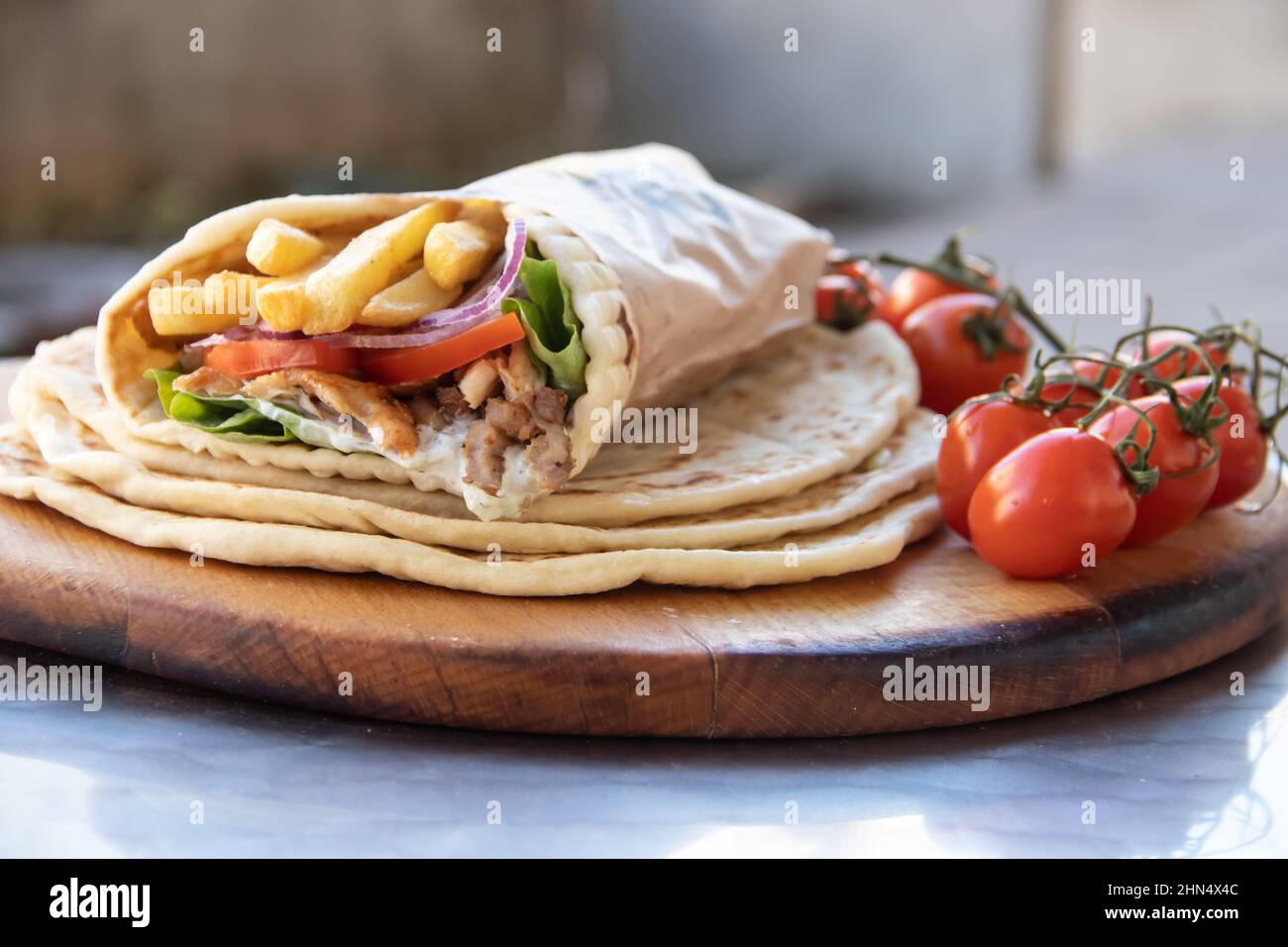 Griechisches Gyros Street Food zum Mitnehmen, schön verpackt mit Tomaten, Souvlaki, griechischem Salat, Zwiebeln und Pommes frites Stockfoto