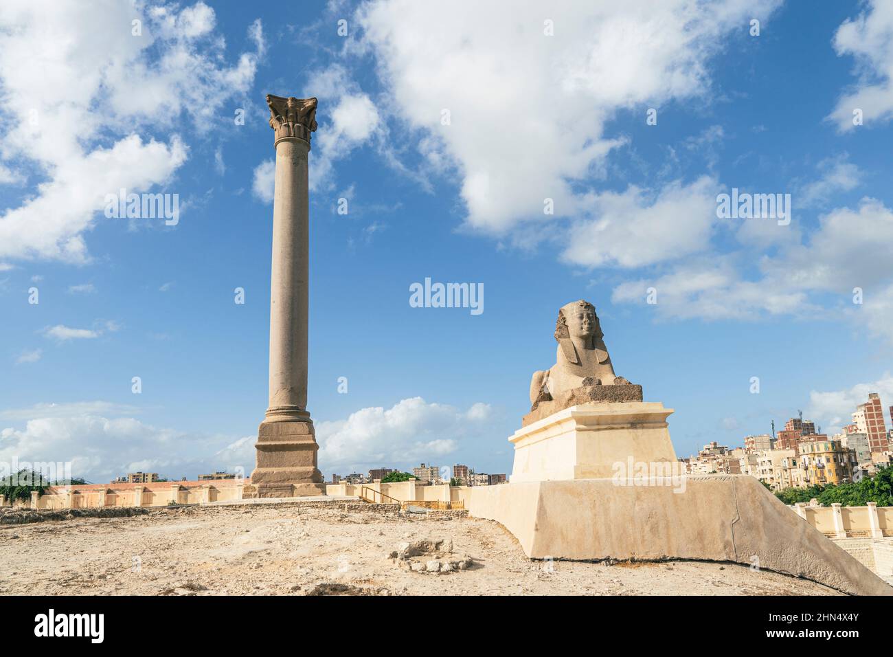 Der berühmte Pompeius-Pfeiler mit einer Sphinx in der oberägyptischen Stadt Alexandria. Ein beliebtes Reiseziel. Tag und blauer Himmel. Eine schöne Langzeitbelichtung Stockfoto