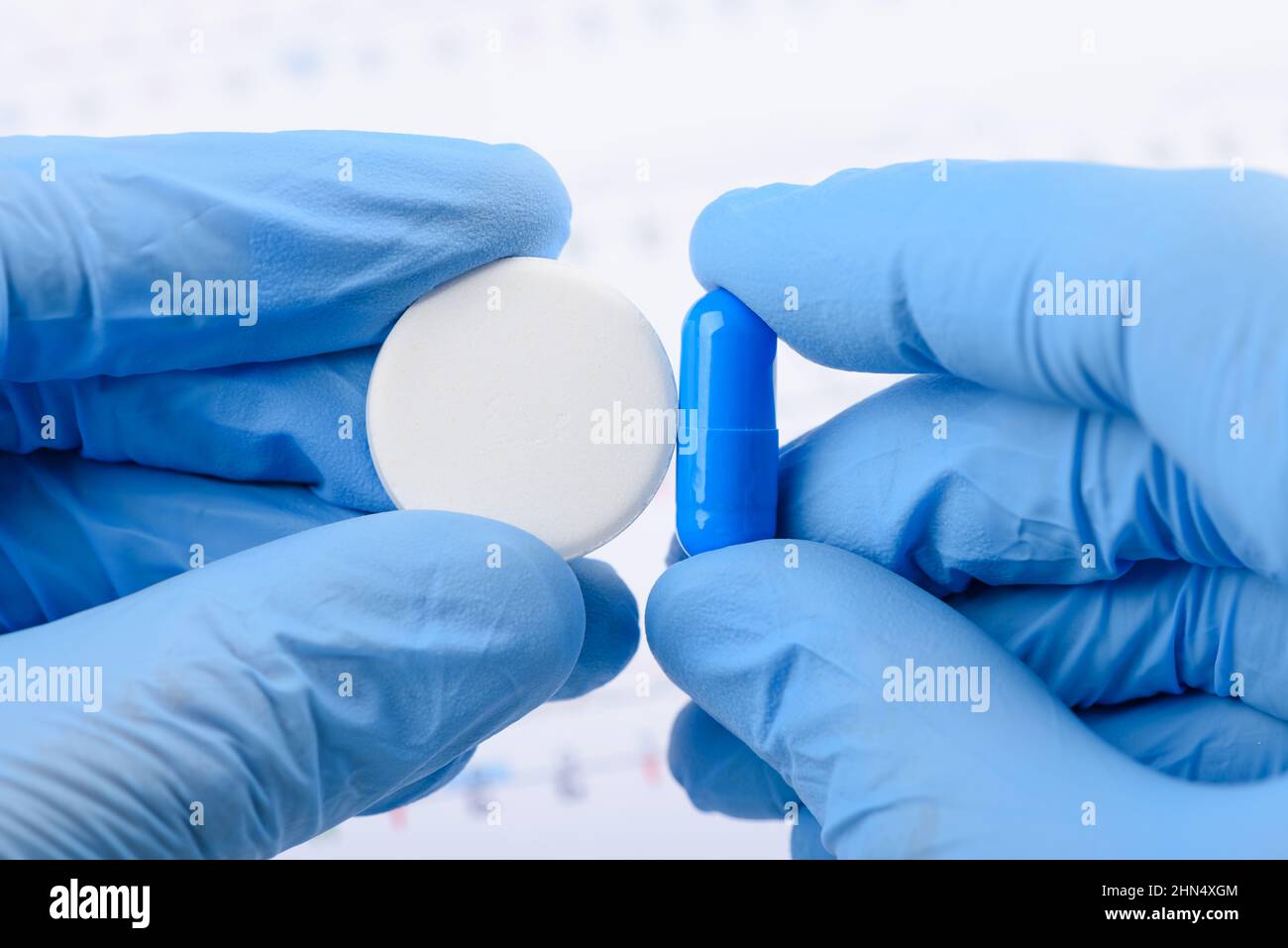 Wissenschaftler halten in den Händen und vergleichen zwei verschiedene Arten von Medikamentenverabreichung große Kohlenstoffpille und kleine Kapsel Stockfoto