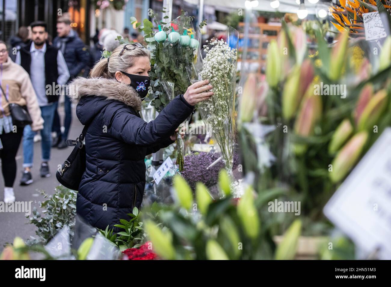 Columbia Road Flower Market beschäftigt mit Ausstellern, die ihre Blumenstände arrangieren und Menschen, die vor dem Valentinstag, East London, Großbritannien, Blumen kaufen Stockfoto