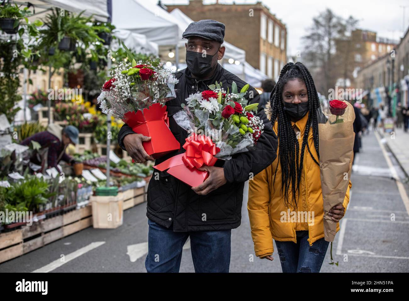 Columbia Road Flower Market beschäftigt mit Ausstellern, die ihre Blumenstände arrangieren und Menschen, die vor dem Valentinstag, East London, Großbritannien, Blumen kaufen Stockfoto