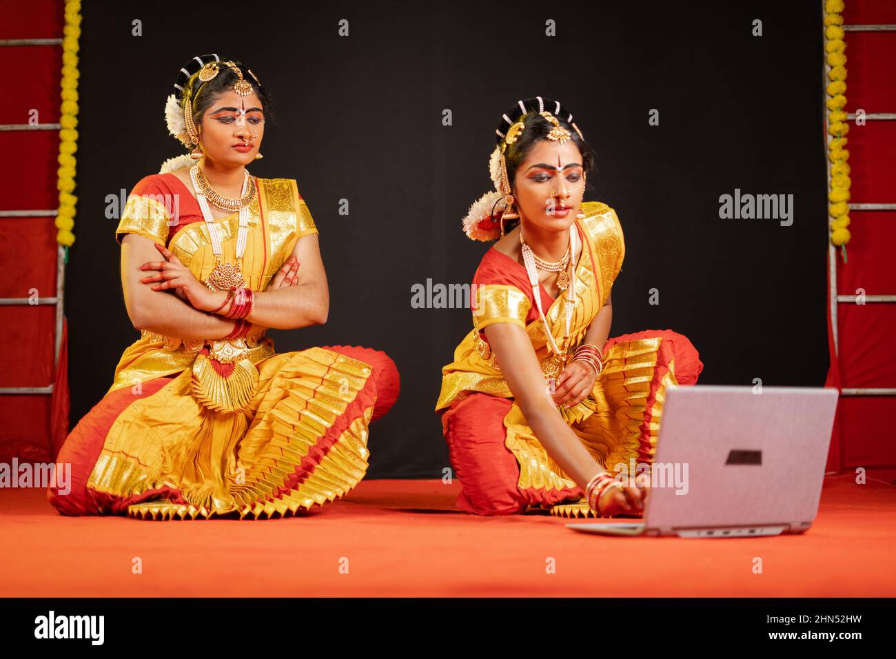 Bharatnatyam-Tänzer sind damit beschäftigt, auf der Tanzbühne Schritte auf dem Laptop zu überprüfen - Konzept der Technologie, Probe, Vorbereitung und Lernen aus dem Internet Stockfoto