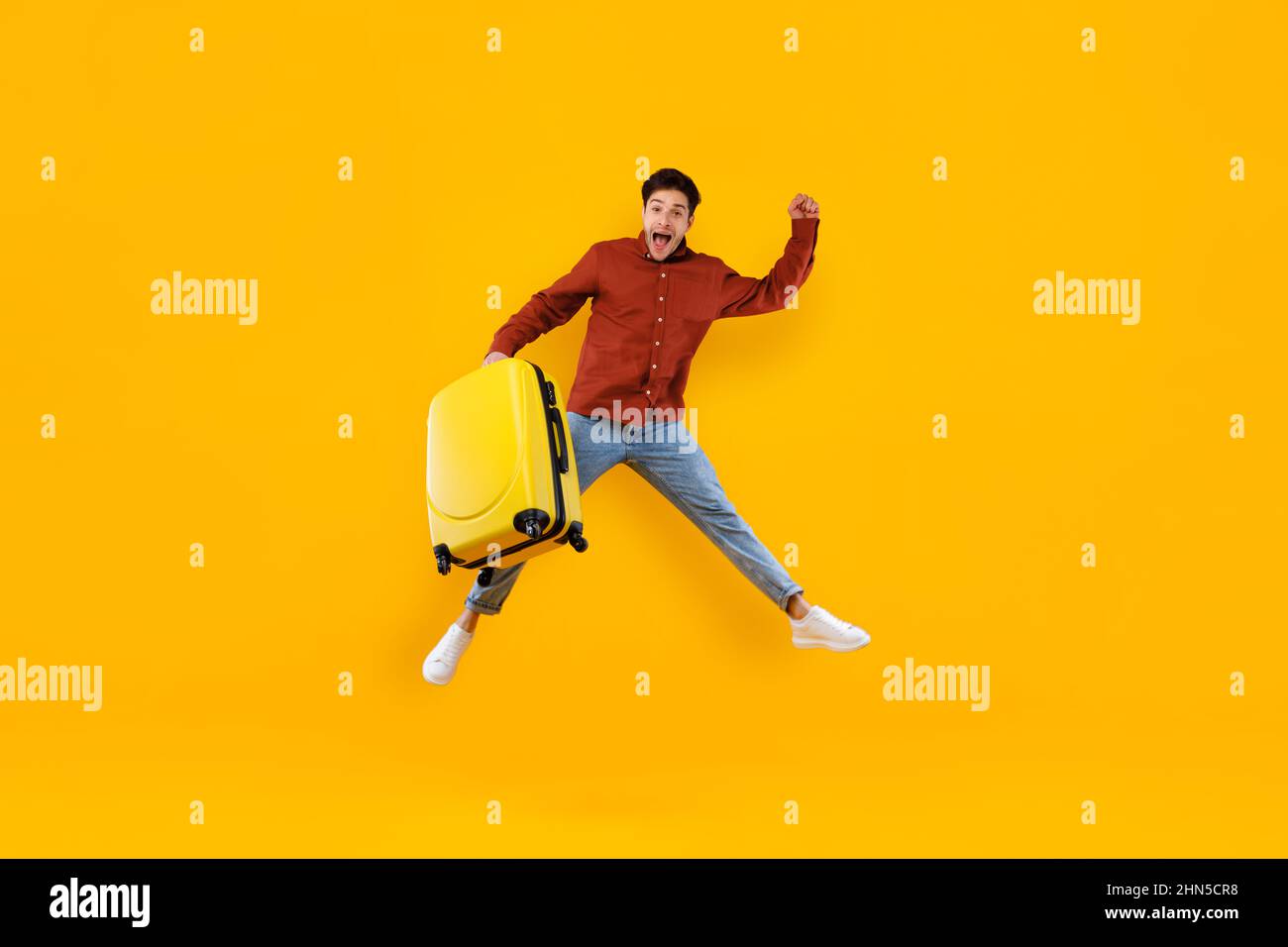 Männlicher Reisender Springt Halten Großen Koffer Über Gelben Hintergrund Stockfoto