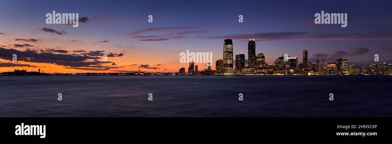 Die Wolkenkratzer in der Innenstadt von Jersey City nach Sonnenuntergang. Blick auf den Hudon River in der Dämmerung von Ellis Island nach Newport, New Jersey Stockfoto