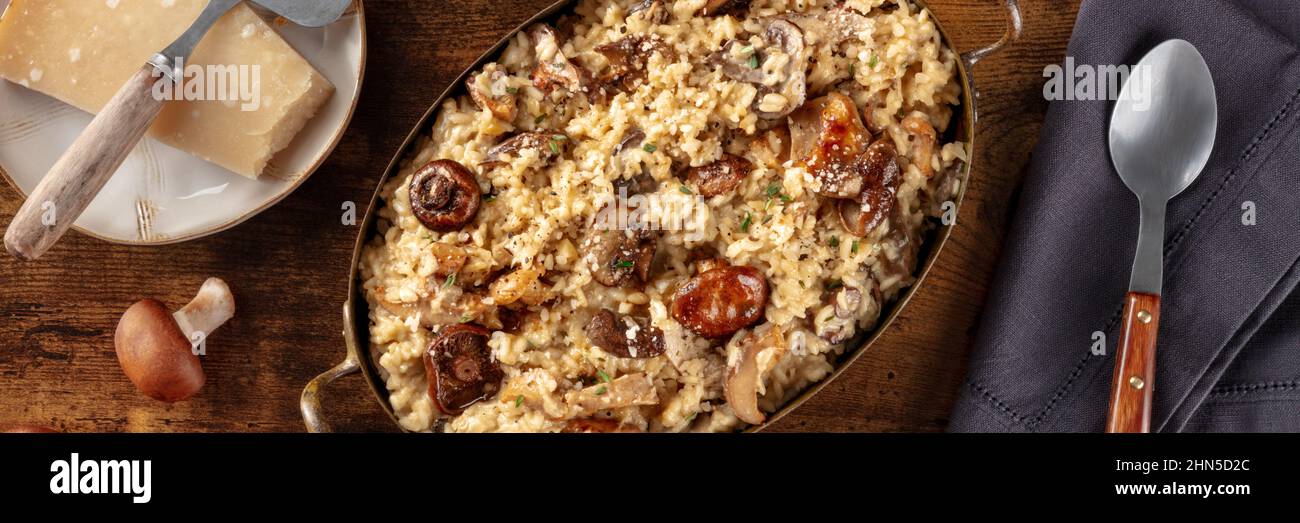 Pilzrisotto-Panorama mit Zutaten auf dunklem, rustikalem Holzhintergrund, Topshot Stockfoto
