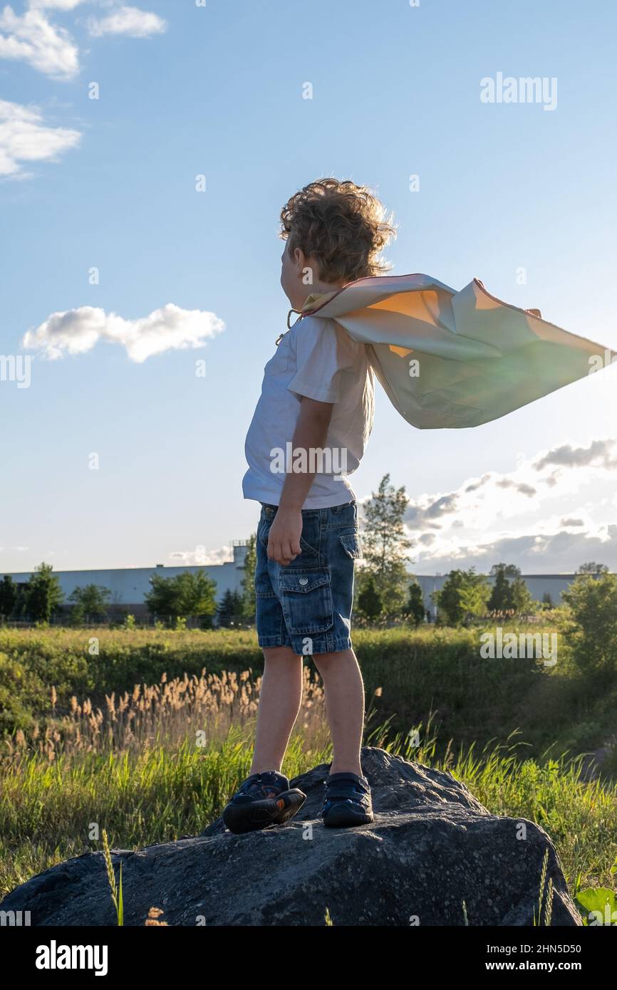 Kleiner Junge, der mit einem Superhelden-Umhang am Horizont sieht. Hochwertige Fotos Stockfoto